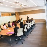 A diverse group actively collaborating in a bright, modern conference room setting.