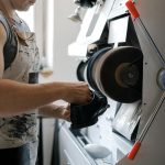 A craftsman skillfully polishes a leather shoe using an industrial machine, showcasing traditional shoemaking.